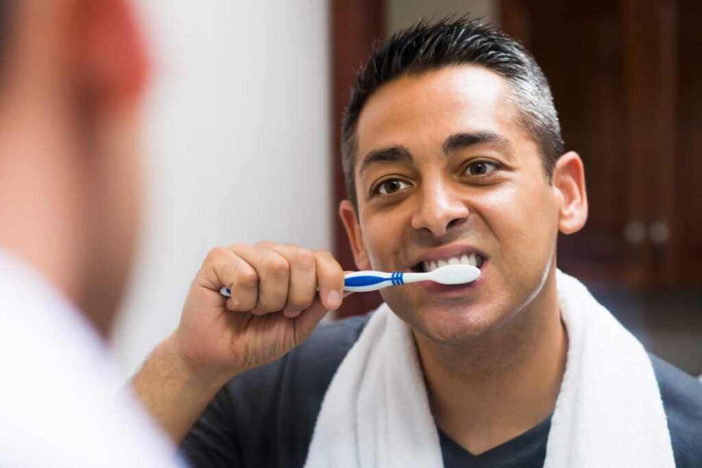 man brushing his teeth with fluoride