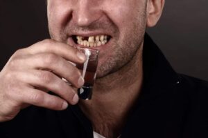 man holding alcohol bottle with bad teeth